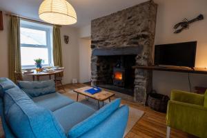 Una sala de estar con un sofá azul y una chimenea. en Ty Bach, en Llanberis