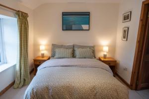 Un dormitorio con una cama con dos lámparas sobre dos mesas. en Ty Bach, en Llanberis