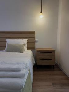 - une chambre avec un lit doté d'une tête de lit en bois et d'une table de chevet dans l'établissement AL44, à Beja