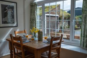 a dining room table with chairs and a large window at Y Berllan in Caernarfon
