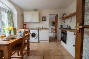 a kitchen with a table and a sink and a dishwasher at Y Berllan in Caernarfon +13 photos