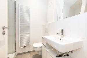 a white bathroom with a sink and a toilet at Cosy Apartment Berlin Neukölln in Berlin +2 photos