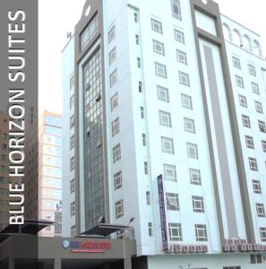a tall white building with a sign on it at Blue Horizon Suites in Manama