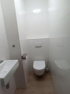 a white bathroom with a toilet and a sink at Au soleil in Świnoujście