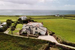 a white house in a field with the ocean at Merlins Cottage in Tintagel