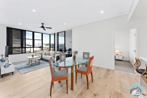 a living room with a glass table and chairs at Aircabin - Shell Cove - Waterview - 2 Bed Apt in Shellharbour