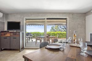 a dining room with a table and a television at Appart Rez de jardin vue mer in Cavalaire-sur-Mer