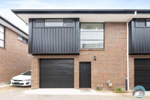 a brick house with two garage doors and a car at Aircabin - Kingswood - Sydney - 3 Beds Townhouse in Kingswood