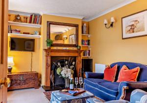 a living room with a blue couch and a fireplace at Devon Cottage - Fittleworth in Fittleworth