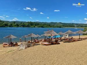 a beach with many chairs and umbrellas on it at Azzurro Apartman Srebrno Jezero in Veliko Gradište