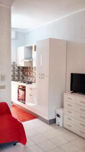 a white kitchen with white cabinets and a tv at Studio with shared pool terrace and wifi at Sciacca in Sciacca