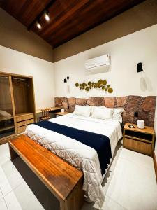 a bedroom with a large bed with a wooden bench at Villa Hortensia in Mucugê