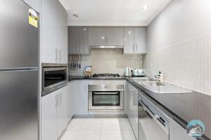 una cocina con armarios blancos y fregadero en Aircabin - Meadowbank - Waterview - 3 Beds Apt en Sídney