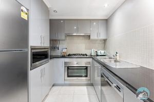 a kitchen with white cabinets and a sink at Aircabin - Meadowbank - Waterview - 3 Beds Apt in Sydney