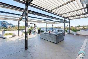 an outdoor patio with awning and furniture on a roof at Aircabin - Meadowbank - Waterview - 3 Beds Apt in Sydney