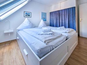 una camera da letto con due letti con lenzuola bianche di Moin a Greetsiel