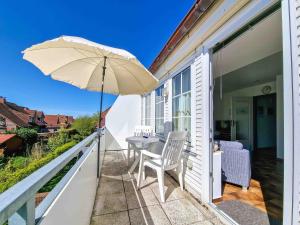 een patio met een tafel en een parasol op een balkon bij Moin in Greetsiel