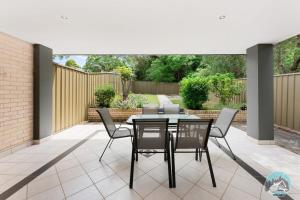 a patio with a table and chairs on it at Aircabin - Telopea - Sydney - 5 Beds Holiday House in Sydney