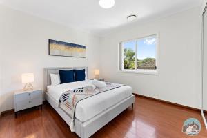 a white bedroom with a bed and a window at Aircabin - Panania - Sydney - Cozy - 5 Beds House in Panania