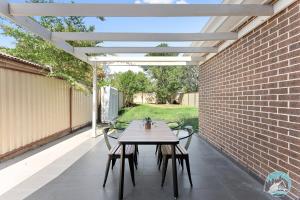 a table and chairs on a patio with a pergola at Aircabin - Panania - Sydney - Cozy - 5 Beds House in Panania