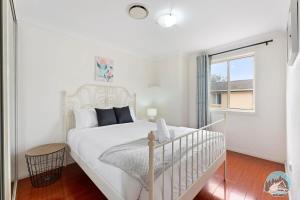 Un dormitorio blanco con una cama blanca y una ventana. en Aircabin - Seven Hills - Lovely - 3 Beds Townhouse, en Blacktown
