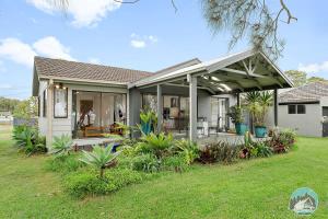 a house with a covered porch with plants at Aircabin - Tuggerawong - Waterfront - 4 Beds House in Karraganbah
