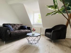 una sala de estar con 2 sofás negros y una mesa. en Gästehaus Theo, en Gotha