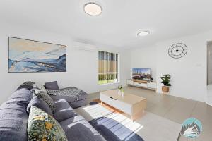 un soggiorno con un divano blu e un tavolo di Aircabin - Edmondson Park - 4 Beds Compy House a Prestons