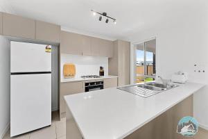 una cucina bianca con un grande piano di lavoro bianco di Aircabin - Edmondson Park - 4 Beds Compy House a Prestons