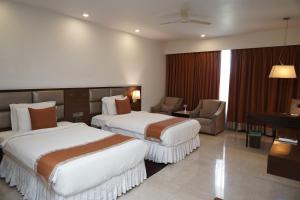 una camera d'albergo con due letti e un pianoforte di The Alcor Hotel a Jamshedpur