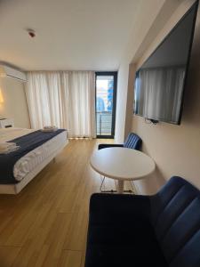 バトゥミにあるOrbi City Hotelのベッド、テーブル、椅子が備わるホテルルームです。