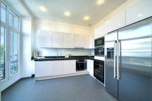 La cuisine est équipée de placards blancs et d'un réfrigérateur en acier inoxydable. dans l'établissement Appartement Francis F. Copolla, à Cannes