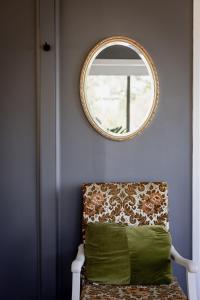 a mirror on a wall with a chair and a window at 'Lazy Susan's' Waterfront Shack in Primrose Sands