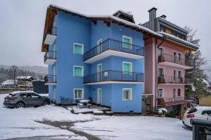 ein blaues Gebäude mit einem Parkplatz im Schnee in der Unterkunft House Cuel Milena Folgaria - Yellow in Folgaria