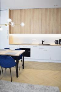 a kitchen with white cabinets and a table and a sink at Apartos Seaside Garden Apartments I in Świnoujście