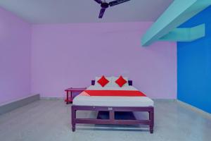 ein Schlafzimmer mit einem Bett mit roten Kissen darauf in der Unterkunft OYO Flagship Kallalagar Hotel 