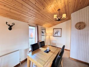 a dining room table with chairs and a clock on the wall at Lomond 5 with Private Hot Tub - Fife - Loch Leven - Lomond Hills - Pet Friendly in Kelty