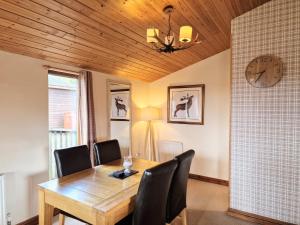 a dining room with a table and chairs and a clock at Lomond 5 with Private Hot Tub - Fife - Loch Leven - Lomond Hills - Pet Friendly in Kelty