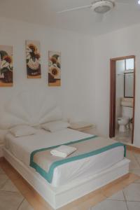 a white bed in a bedroom with a bathroom at Hotel Manzana Blanca 5th Avenue in Playa del Carmen