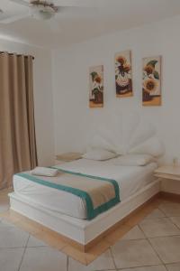 a white bed in a room with pictures on the wall at Hotel Manzana Blanca 5th Avenue in Playa del Carmen