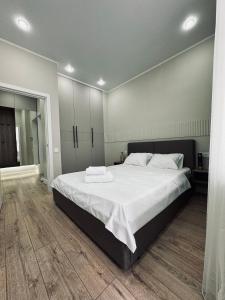 een slaapkamer met een groot bed met witte lakens bij 2-х комнатные апартаменты в ЖК GreenLine.Asyl Mura in Taldykolʼ