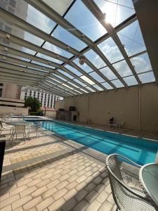 a swimming pool with chairs and a glass ceiling at Flat Hotel Aeroporto Congonhas UH1109 in São Paulo