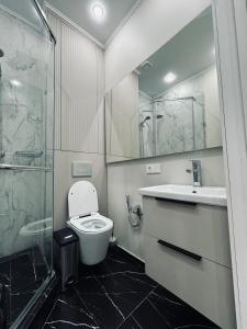 een badkamer met een toilet, een wastafel en een douche bij 2-х комнатные апартаменты в ЖК GreenLine.Asyl Mura in Taldykolʼ