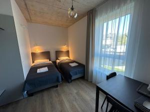 a bedroom with two beds and a table and a window at Tilzes Studio apartaments, Self check-in, Free parking, Comfort in Klaipėda