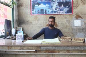 ハリドワールにあるHotel Shree Chitra Residency By Avadhesh Group of Hospitalityの本を持つ机に座る男