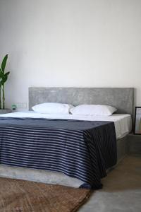 um quarto com uma cama com uma cabeceira cinzenta e almofadas em VIVO Brand New Beach Studio Hot Water Fast Internet em Ahangama