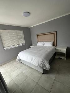 Un dormitorio con una gran cama blanca y una ventana en Grandview adventure and guesthouse en East London