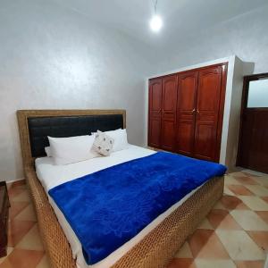 uma cama com um cobertor azul e um armário de madeira em Cozy Appartement in Midelt em Midelt