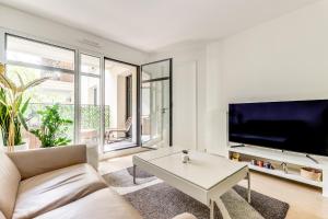 een woonkamer met een bank, een tv en een tafel bij Chic appartement en plein coeur de Levallois-Perret in Levallois-Perret