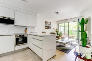 uma cozinha com armários brancos e um cacto em Chic appartement en plein coeur de Levallois-Perret em Levallois-Perret